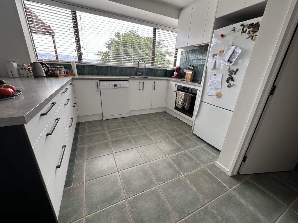 Flat pack kitchen install with island bench, bar stools, and tiled floor completed by experienced kitchen installers